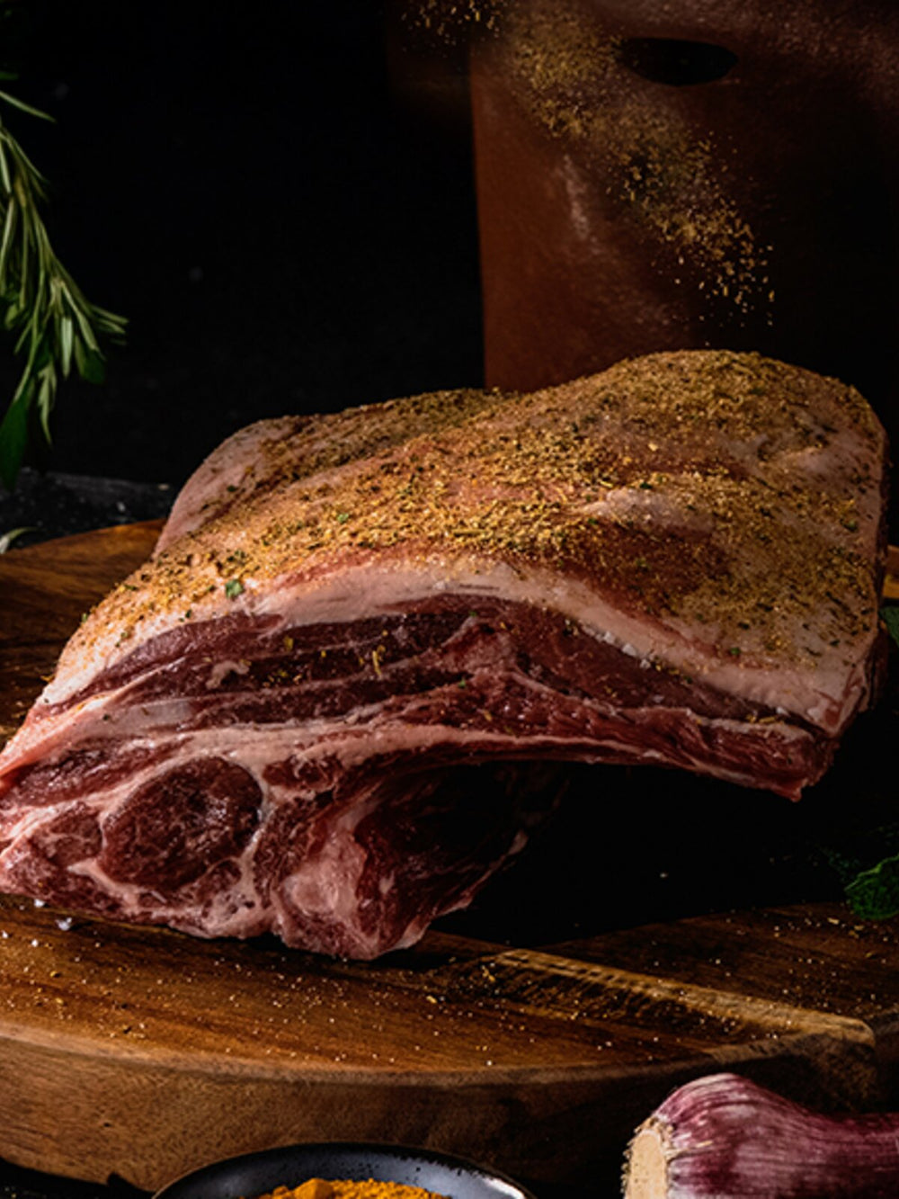 Lamb shoulder with rub and seasonings on wooden board (portrait)